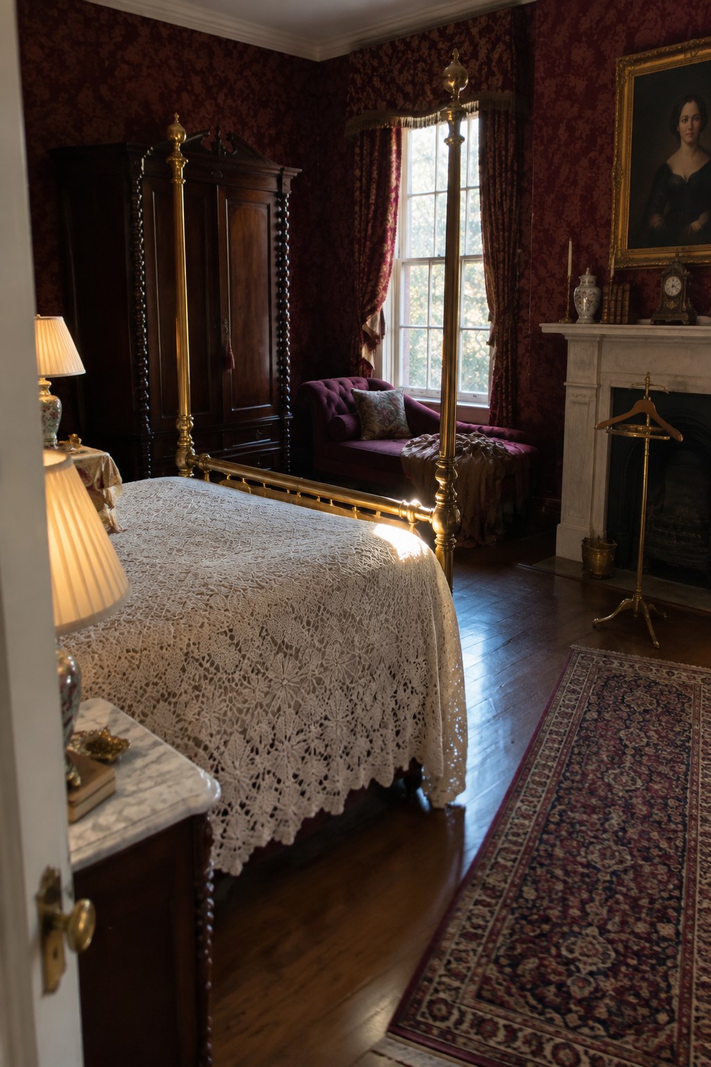A bedroom interior featuring a brass four-poster bed with a white lace coverlet, a dark wood armoire, a purple chaise lounge, red damask wallpaper, and a white fireplace mantel with a portrait above it.