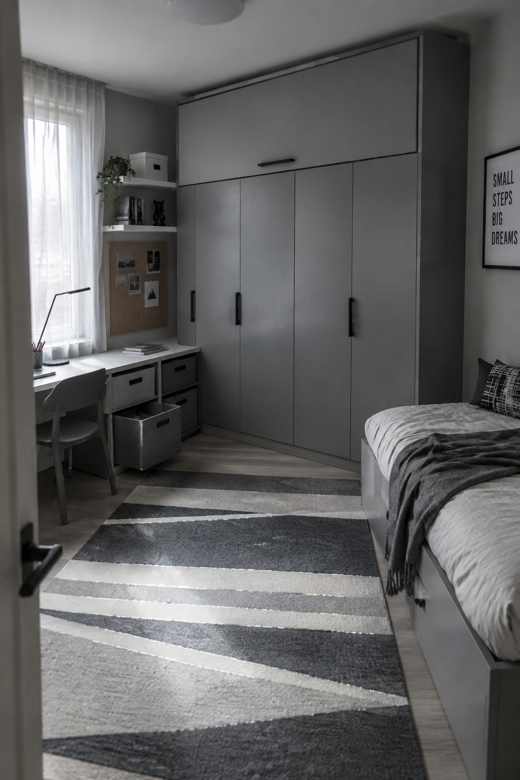 A modern kids bedroom featuring a large gray wardrobe, a desk with multiple storage bins, a bed with white and gray bedding, and a striped rug on light wood flooring.