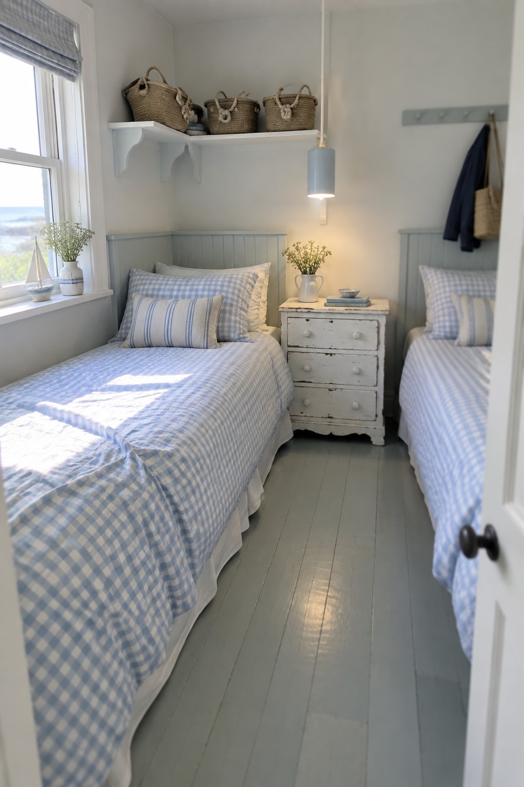 A small bedroom with two twin beds in blue gingham bedding placed on opposite walls and a white distressed dresser between them.