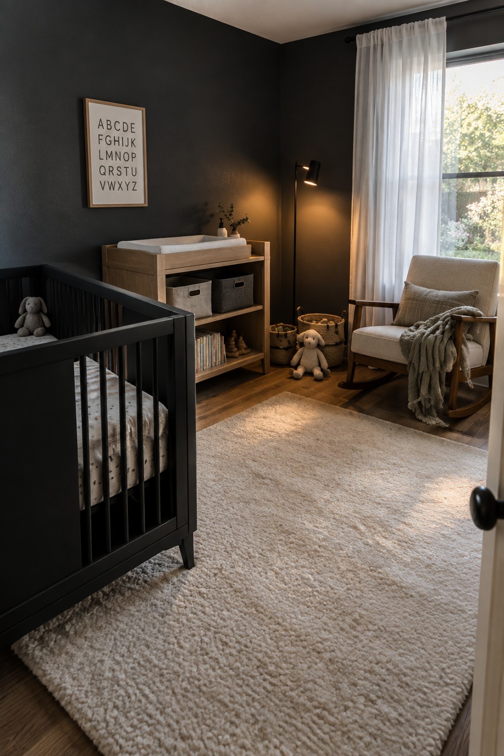 A nursery interior with a black crib, light wood changing table and shelves, a rocking chair, and a large beige rug on dark walls.