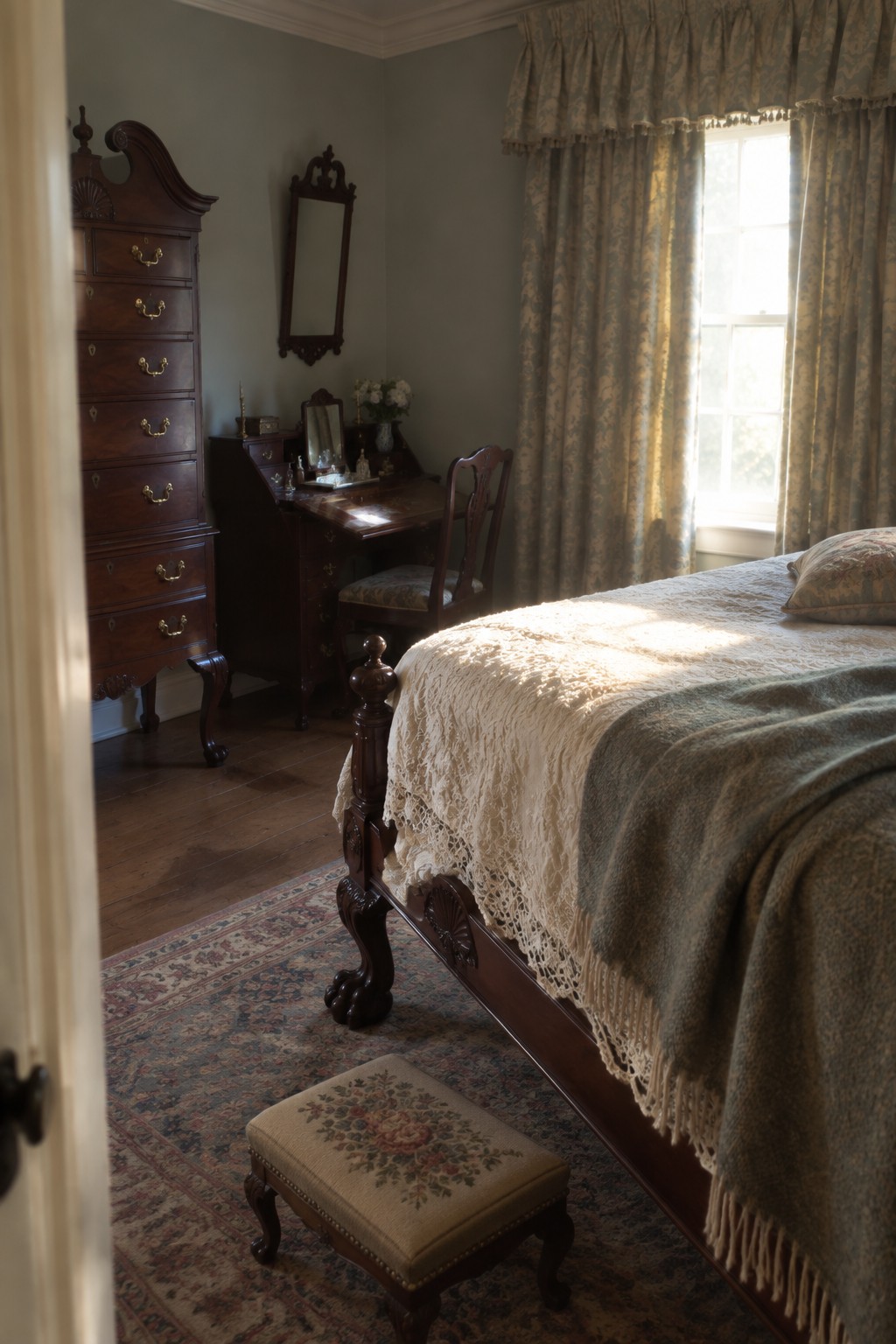 Traditional bedroom with dark wood highboy chest, vanity desk, and four-poster bed on a patterned rug.