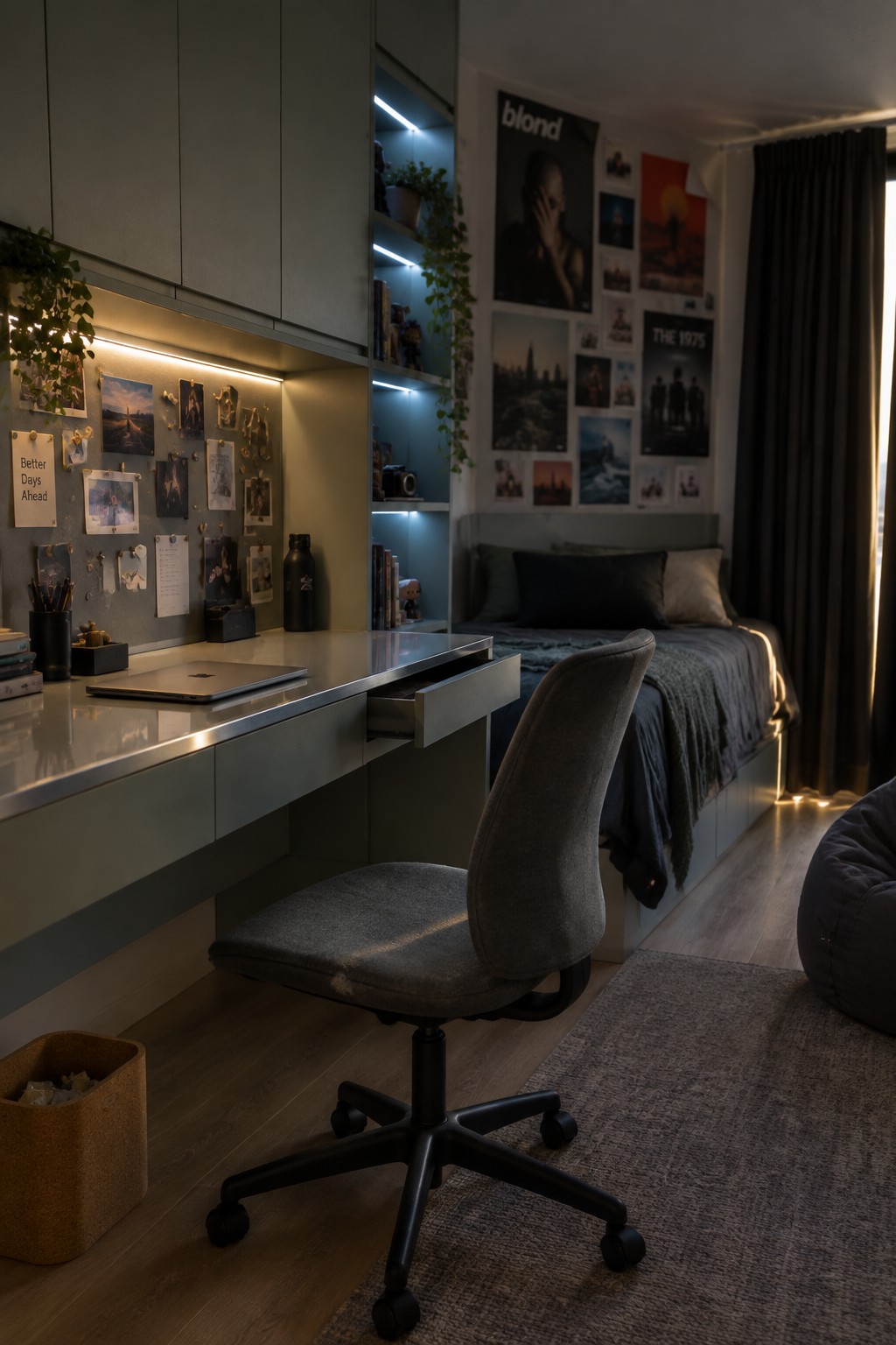 A small bedroom with a built-in desk, open drawer, gray office chair, wall-mounted storage units, and a bed with posters on the wall behind it.